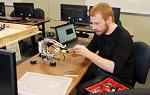 一个学生在计算机实验室里摆弄一个乐高机器人. 